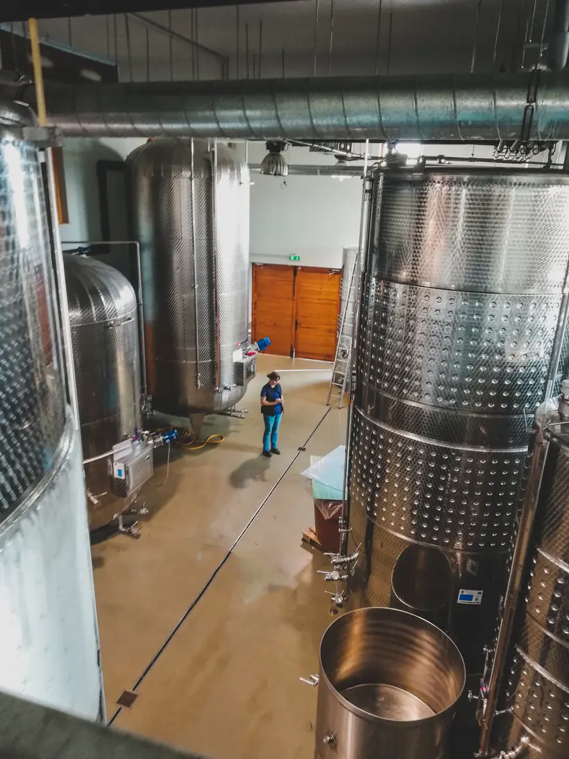 Profesional inspeccionando tanques de acero inoxidable en una planta de procesamiento de alimentos